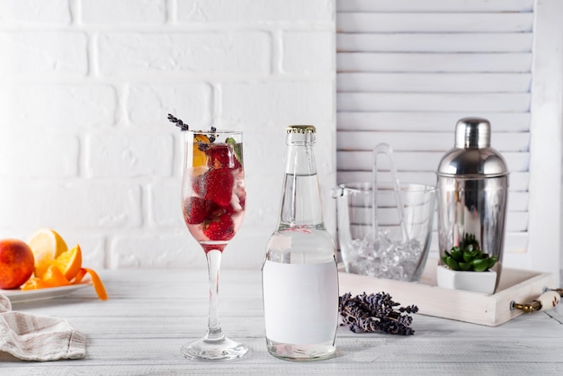 Cocktail rouge avec glace et fraise, lavande avec une bouteille de tonique sur la bouteille