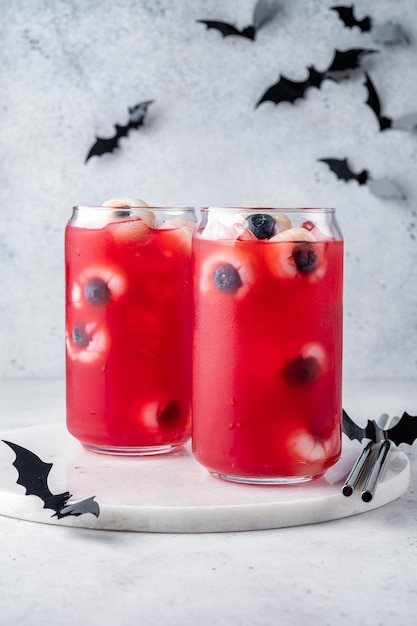 Cocktail rouge d'halloween avec des globes oculaires de litchi et de myrtille