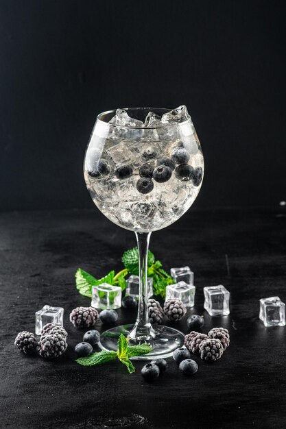 Cocktail transparent avec myrtille et glace sur fond noir