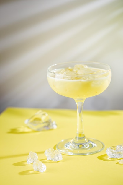 Cocktail tropical de banane fraîche et de noix de coco dans un verre sur fond jaune