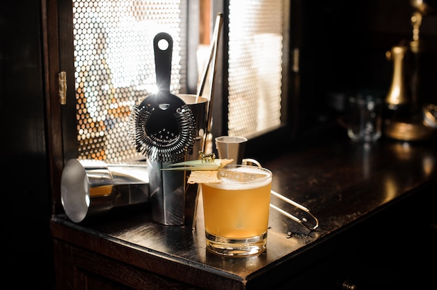 Cocktail et ustensiles d'été alcoolisés décorés de jaune frais et aigre disposés sur la table de bar