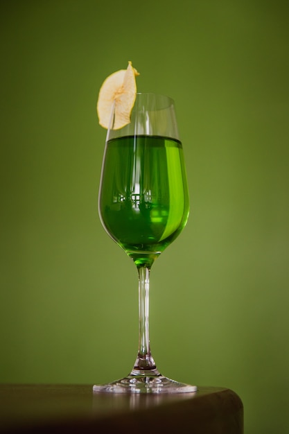 Un cocktail vert dans un verre à flûte garni d'une tranche de pomme déshydratée