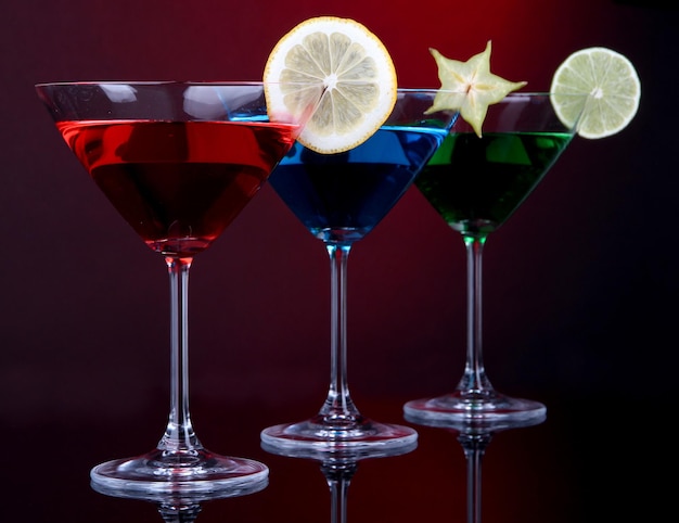 Cocktails alcoolisés dans des verres à martini sur fond rouge foncé