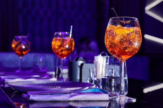 Cocktails alcoolisés avec de la glace et des morceaux d'orange sur la table servie de la discothèque