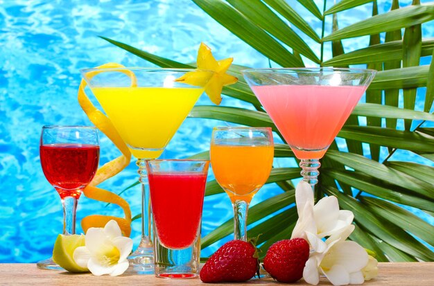 Photo cocktails exotiques et fleurs sur table sur fond de mer bleue