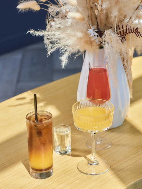 Cocktails sur la table différentes boissons colorées dans différents verres sur une table en bois sombre sur flou