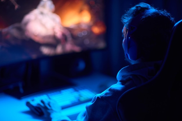 Un codeur travaille tard dans la nuit sur un écran d'ordinateur en codant et en utilisant une application pour smartphone
