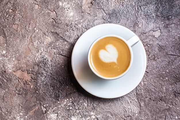 Coeur d'art latte dans une tasse de cappuccino. Vue de dessus sur fond de béton marron
