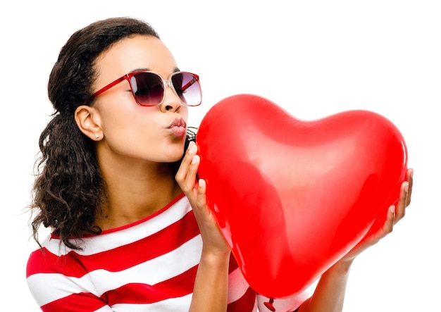 Coeur baiser et saint valentin avec une femme noire en studio isolée sur fond blanc pour l'amour ou la romance Rouge romantique et rencontres avec une femme tenant un symbole d'icône ou un emoji sur un espace vide