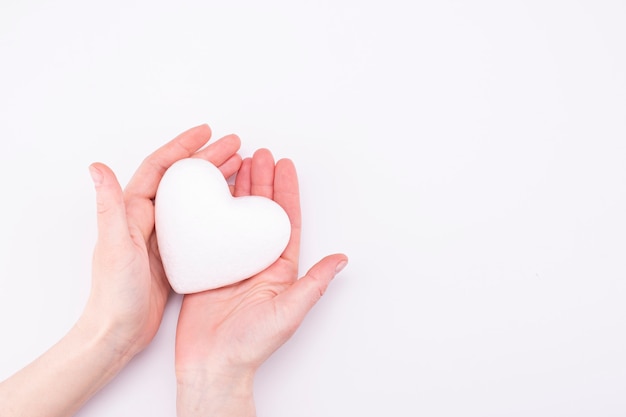 Coeur blanc en mains féminines isolé sur fond blanc avec place pour le texte