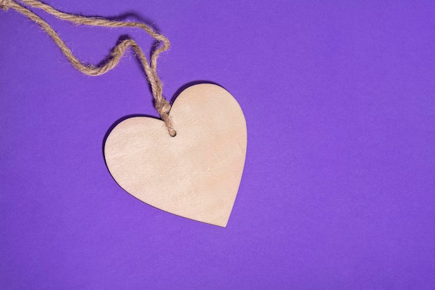 Coeur en bois avec une corde sur fond violet