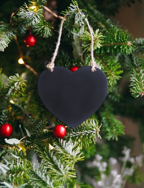 Coeur en bois noir sur fond vert de branches de sapin. Composition de Noël Nouvel An. Moke up, copiez l'espace pour la Saint-Valentin.