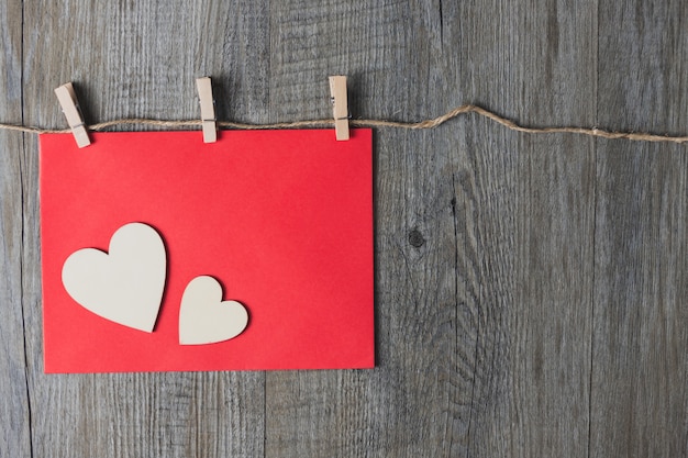 Un coeur en bois posé sur une enveloppe rouge Et posé sur une table en bois gris