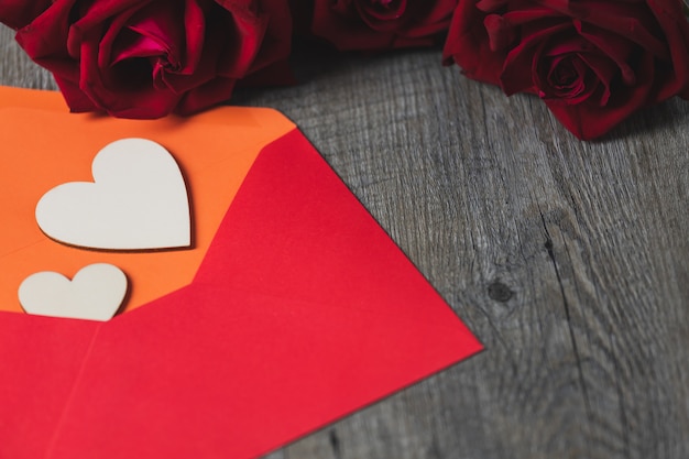 Un coeur en bois posé sur une enveloppe rouge Et posé sur une table en bois gris