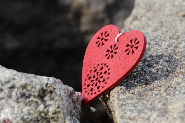 Coeur en bois rouge allongé sur une grosse pierre