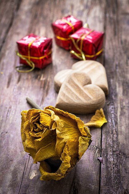 Coeur en bois symbolique sculpté à la main sur un fond de roses jaunes