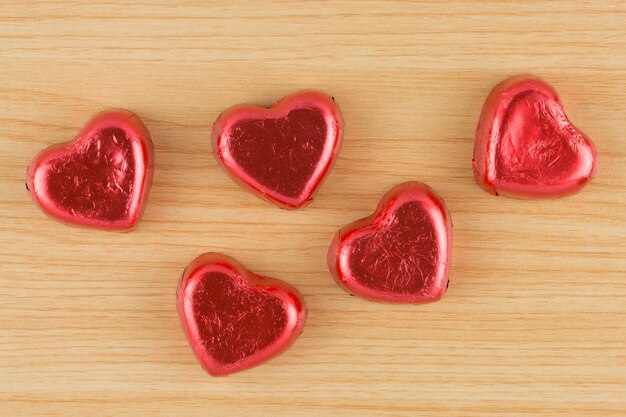 Coeur de bonbons au chocolat rouge sur fond en bois.