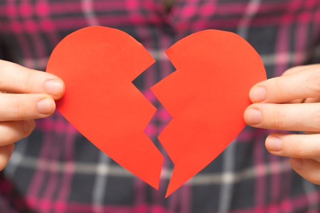 Photo cœur brisé. notion de saint valentin. femme tenant le cœur brisé dans ses mains