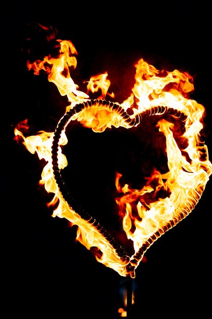 Photo cœur brûlant avec des flammes isolé sur un fond sombre spectacle de feu dans la nuit carte de joyeux jour de la saint-valentin bengale feu brûlant l'espace du cœur pour le texte mariage ou concept de saint valentin bonne année