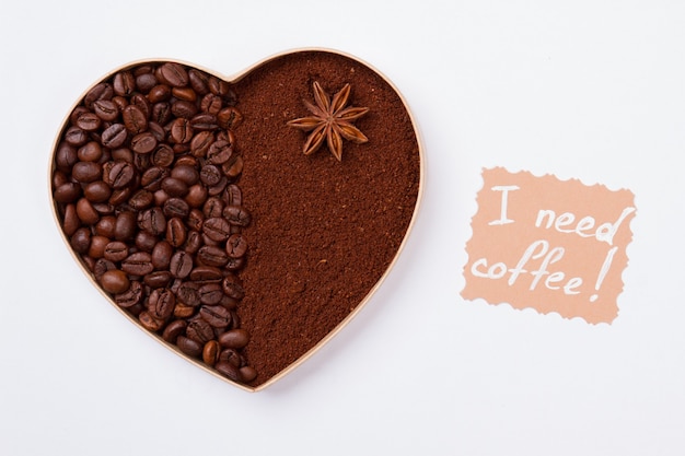 Coeur de café fait de grains et de poudre de café instantané. Isolé sur mur blanc, j'ai besoin de café.