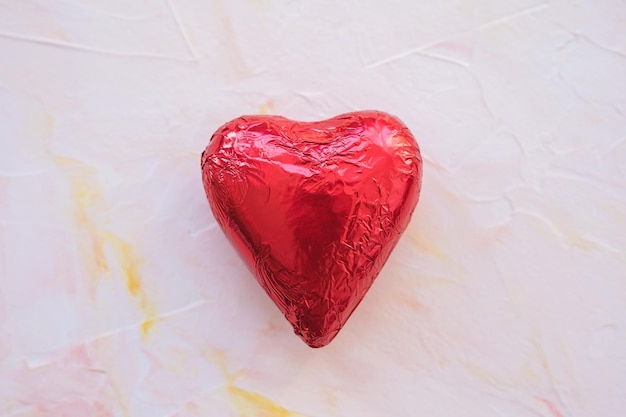 Coeur de chocolat en feuille rouge sur fond rose