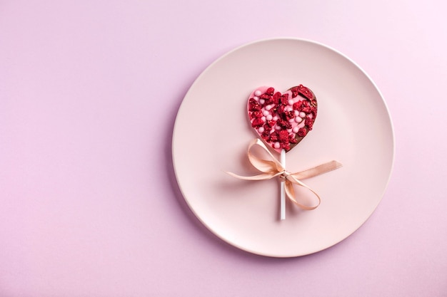 coeur de chocolat sur une plaque rose sur fond rose le concept d'un dîner romantique saint valentin