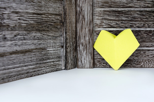 Un coeur de couleur jaune de papier se dresse sur le fond d&#39;une planche de bois sombre