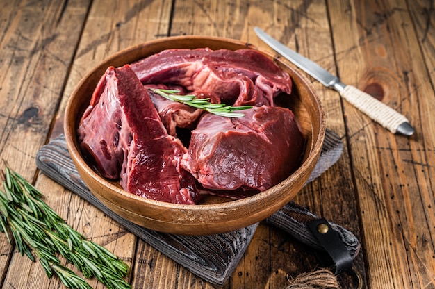 Coeur cru de boeuf ou de veau tranché dans une assiette en bois aux herbes