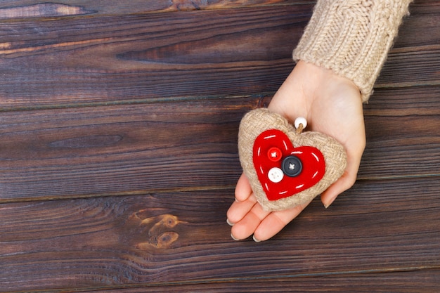 Avec coeur dans les mains sur fond en bois. Concept de la Saint-Valentin