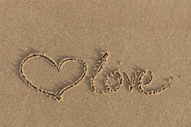 Coeur dessiné dans le sable avec l'amour d'inscription.