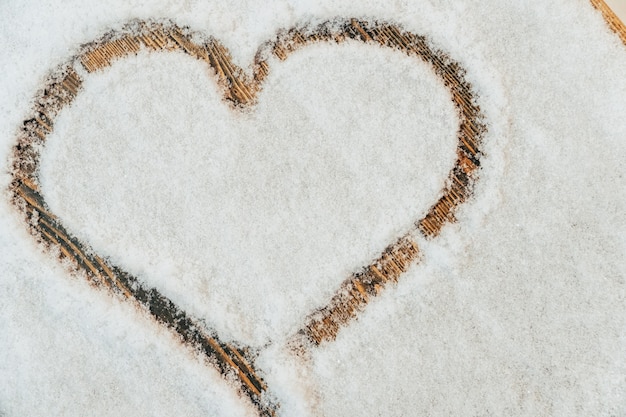 Un coeur dessiné avec un doigt sur la neige