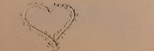 Coeur dessiné sur le sable humide à côté de la mer