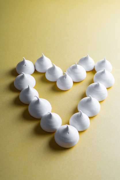 Coeur disposé de meringues sur fond jaune