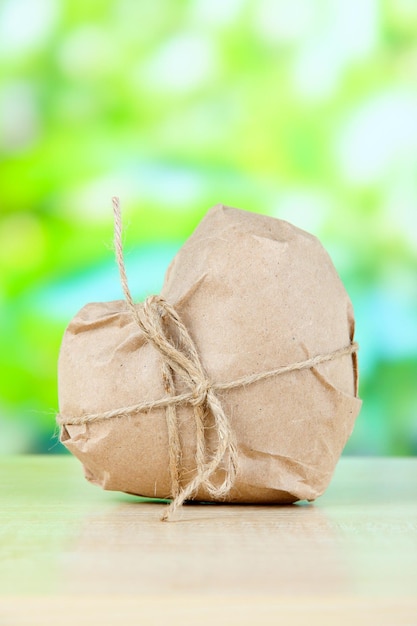 Coeur enveloppé dans du papier kraft brun, sur fond de nature