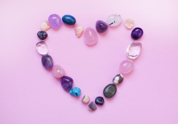 Le cœur est tapissé de minéraux naturels. Pierres semi-précieuses de différentes couleurs, brutes et travaillées. Améthyste, quartz rose, agate, apatite, aventurine sur fond rose