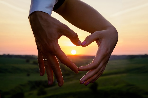 Coeur fait de mains sur fond coucher de soleil coucher de soleil romantique ensemble