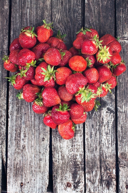 Photo coeur de fraises mûres sur bois