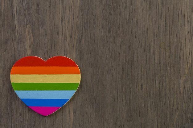 Coeur de Gay Pride arc-en-ciel sur fond de bois.