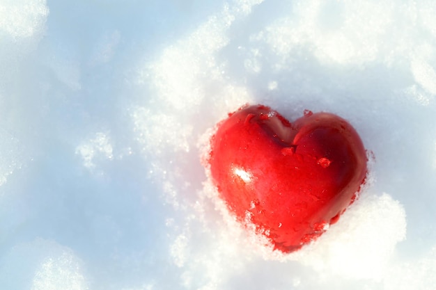 Coeur gelé rouge sur fond de neige