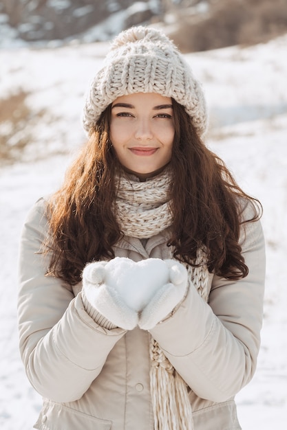 Coeur de neige dans les mains de la femme à l'extérieur