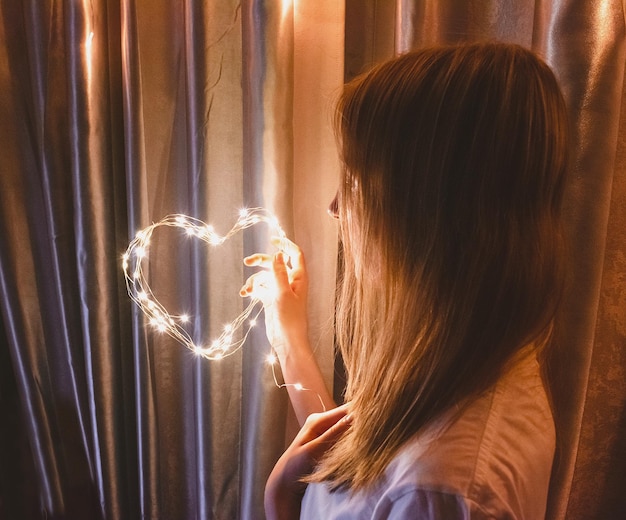 Coeur de nombreuses lumières entre les mains d'une fille