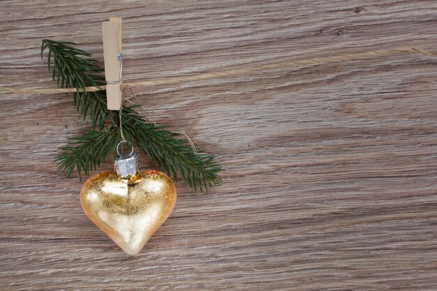 Coeur d'or de Noël avec brindille à feuilles persistantes accroché sur clotheline