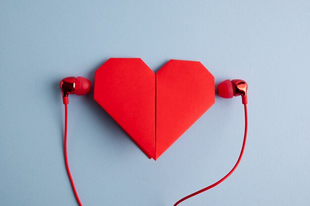 Coeur origami rouge avec un casque sur table bleue