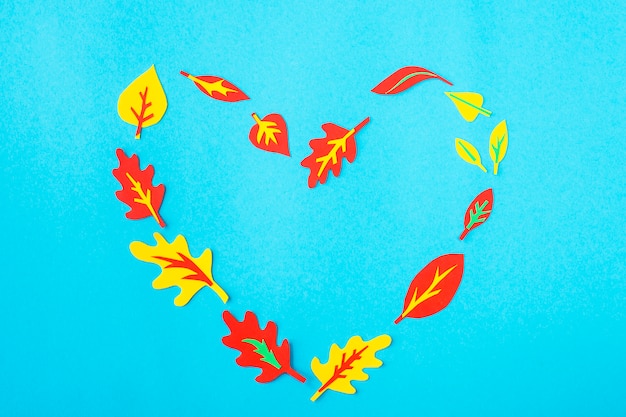 Coeur de papier appliqué de feuilles d&#39;automne sur un fond bleu