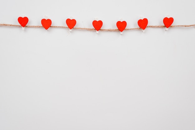 Coeur de papier rouge accroché à la corde à linge sur le mur blanc