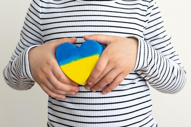 Coeur peint aux couleurs du drapeau de l'ukraine dans les mains des enfants