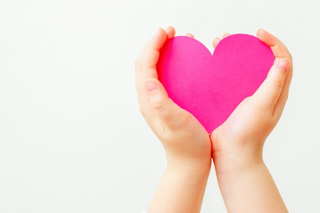 Coeur rose en papier dans les mains de l'enfant.