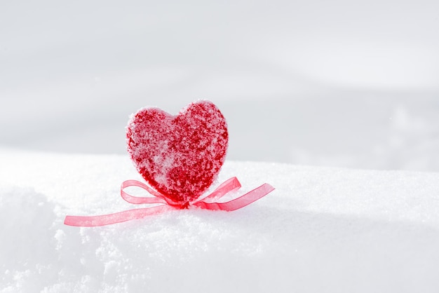 Coeur rouge avec un arc dans la neige