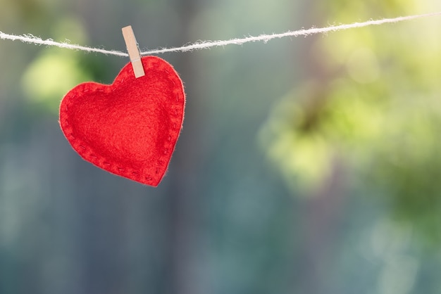 Coeur rouge attaché avec une pince à linge sur fond flou. Concept de la Saint-Valentin avec espace de copie pour le texte publicitaire