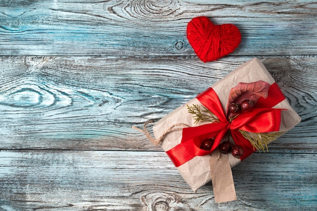 Coeur rouge et boîte-cadeau sur fond en bois gris-bleu.